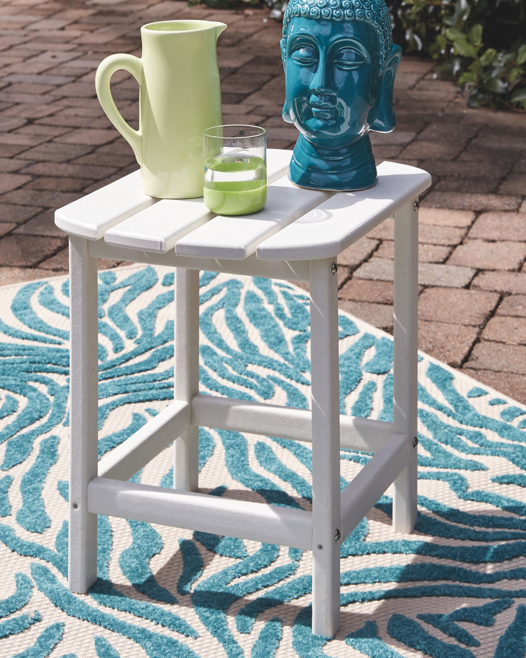 White side table with lower shelf and tabletop; blue patterned outdoor rug