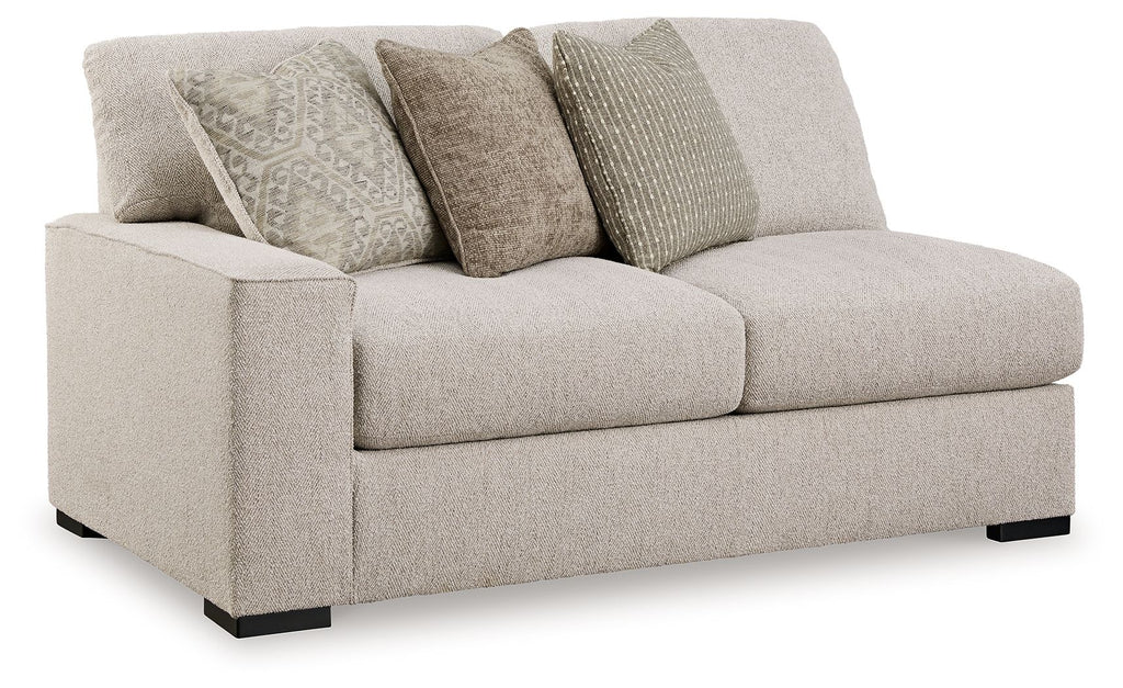 Sand-tone upholstered loveseat with two seat cushions and four patterned throw pillows
