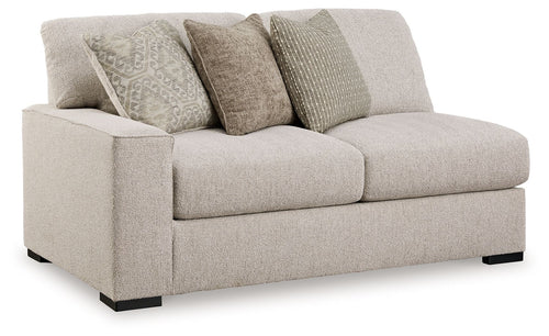 Sand-tone upholstered loveseat with two seat cushions and four patterned throw pillows