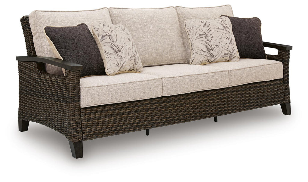 Dark brown wicker sofa with light beige seat and patterned throw pillows
