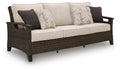 Dark brown wicker sofa with light beige seat and patterned throw pillows