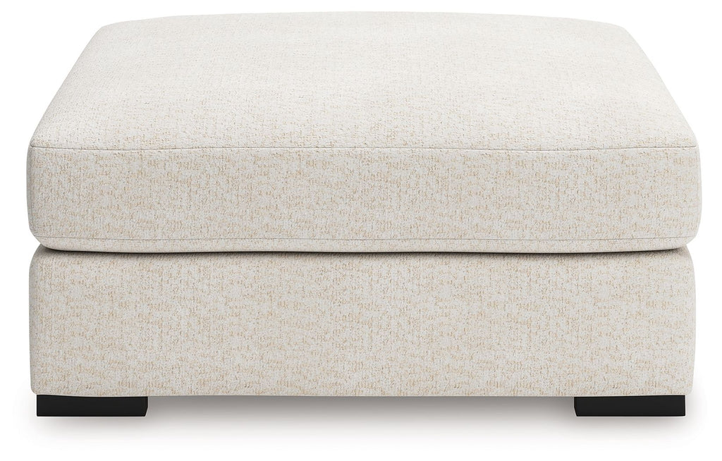 Vanilla upholstered accent ottoman with padded top, black block feet
