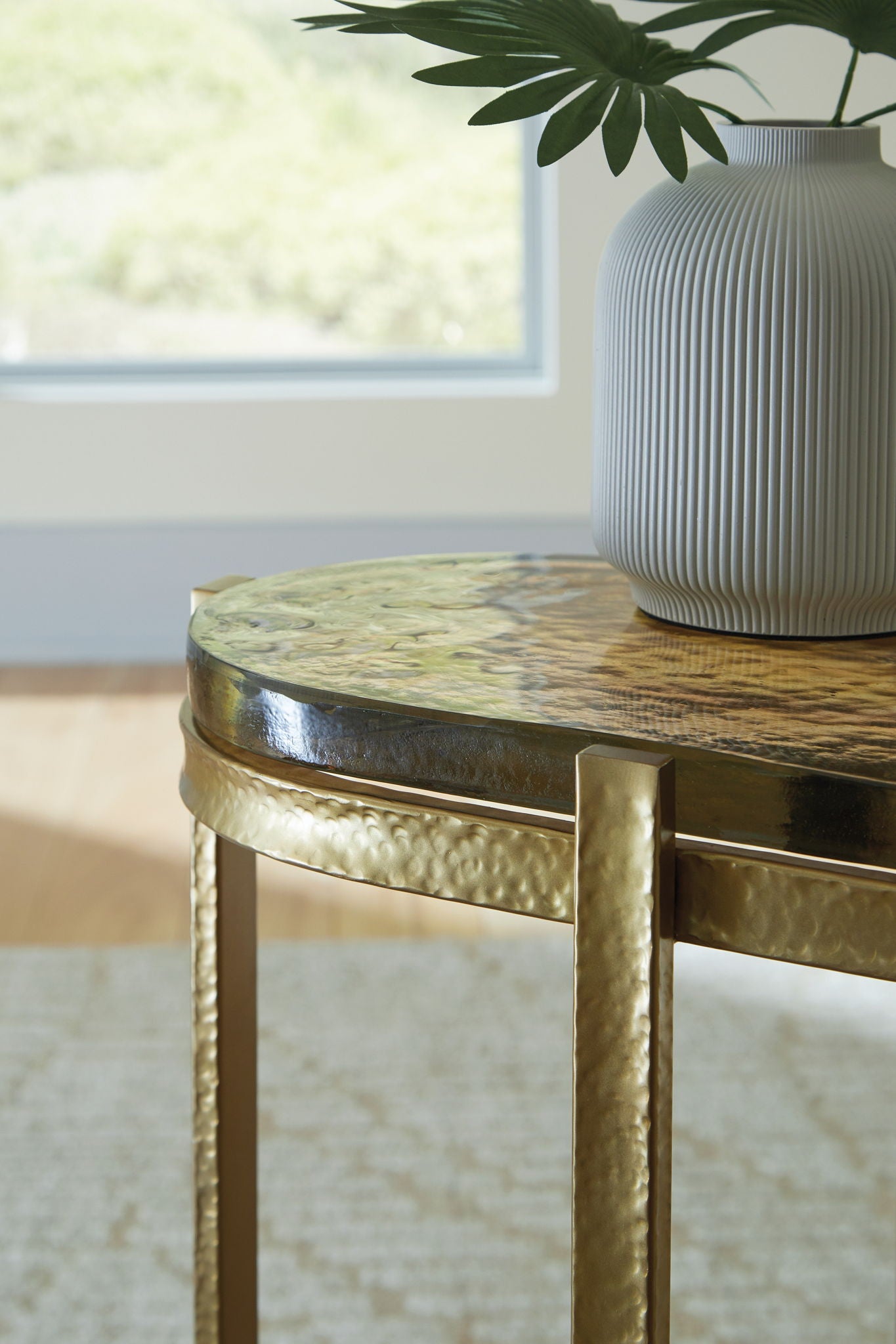 Gold-finish accent table corner detail with round top edge and metal legs