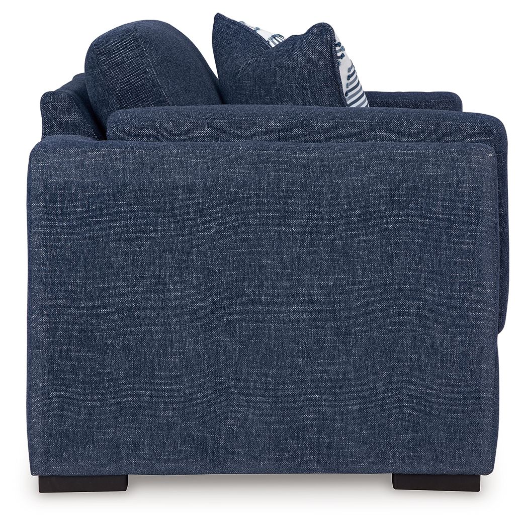 Blue upholstered chair with two striped accent pillows