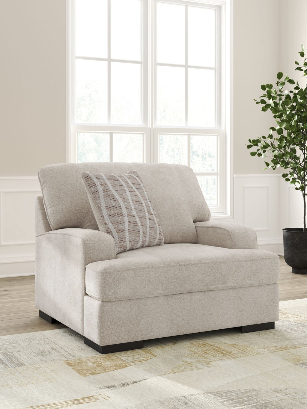 Taupe upholstered chair and a half with striped accent pillow in three-quarter view