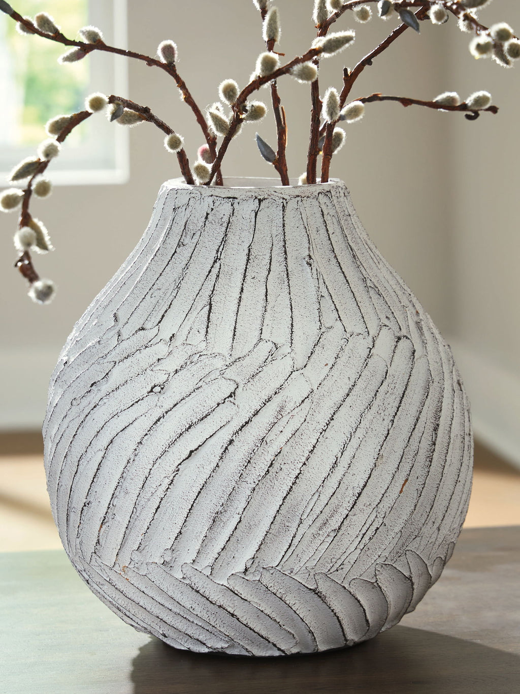 White vase with carved vertical stripes and branches in the opening