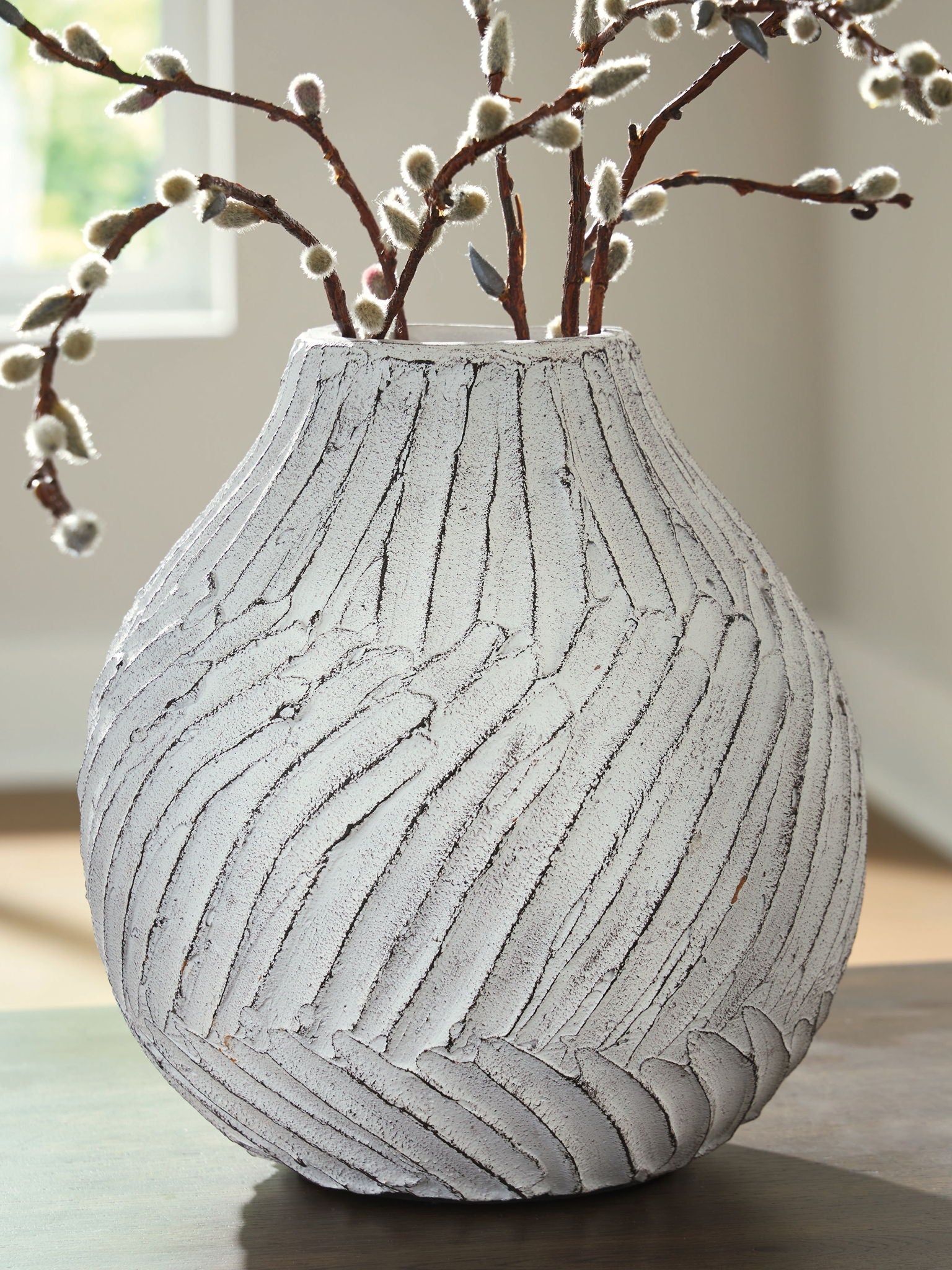 White vase with carved vertical stripes and branches in the opening