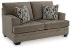 Light beige fabric loveseat with two geometric patterned throw pillows, angled view