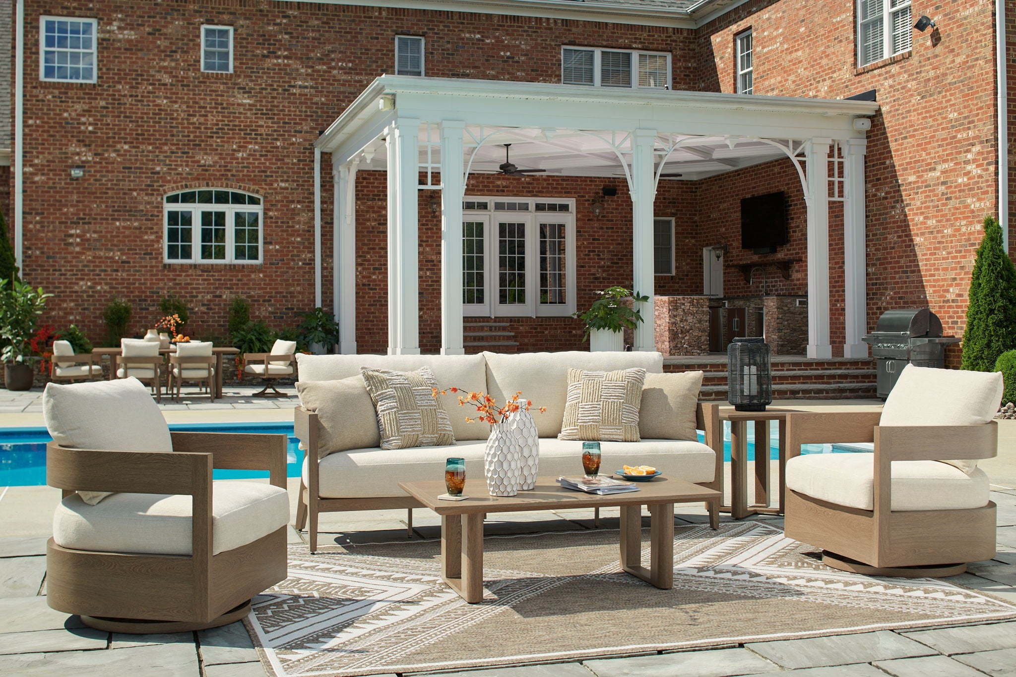 Outdoor lounge seating set with beige cushions, patterned pillows, and coffee table
