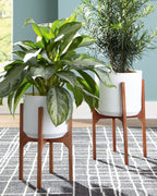 Two white planters on brown wooden stands with potted greenery