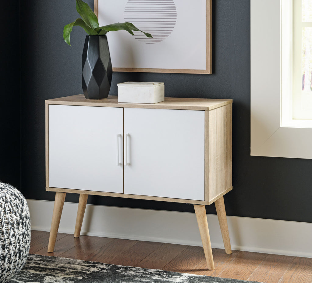 Light wood accent cabinet with two white doors and gold bar handles on angled legs