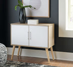 Light wood accent cabinet with two white doors and gold bar handles on angled legs