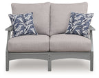 Gray loveseat with two blue palm-pattern throw pillows and centered back cushion