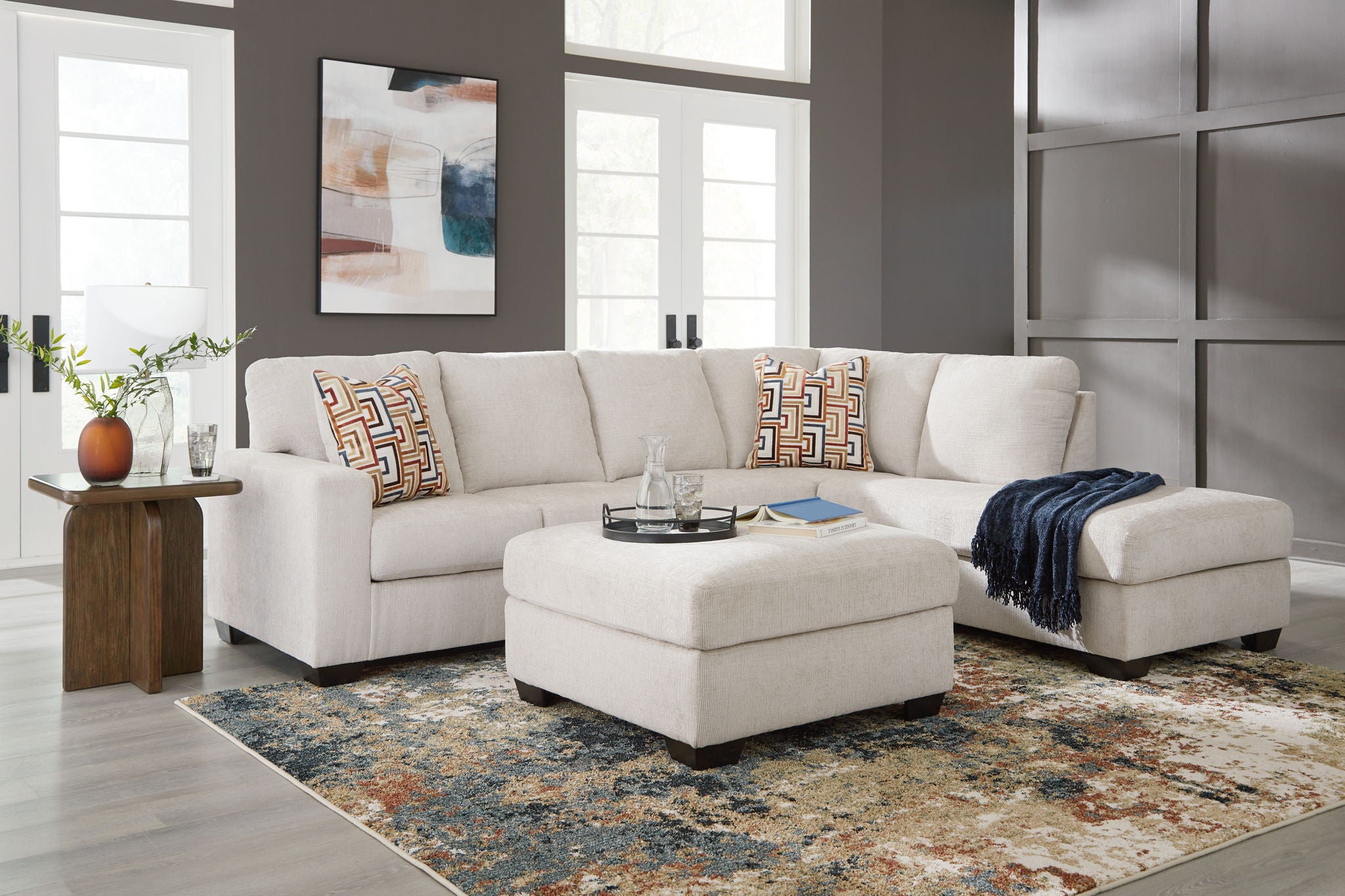 Light beige sectional sofa set with ottoman, chaise, and patterned throw pillows
