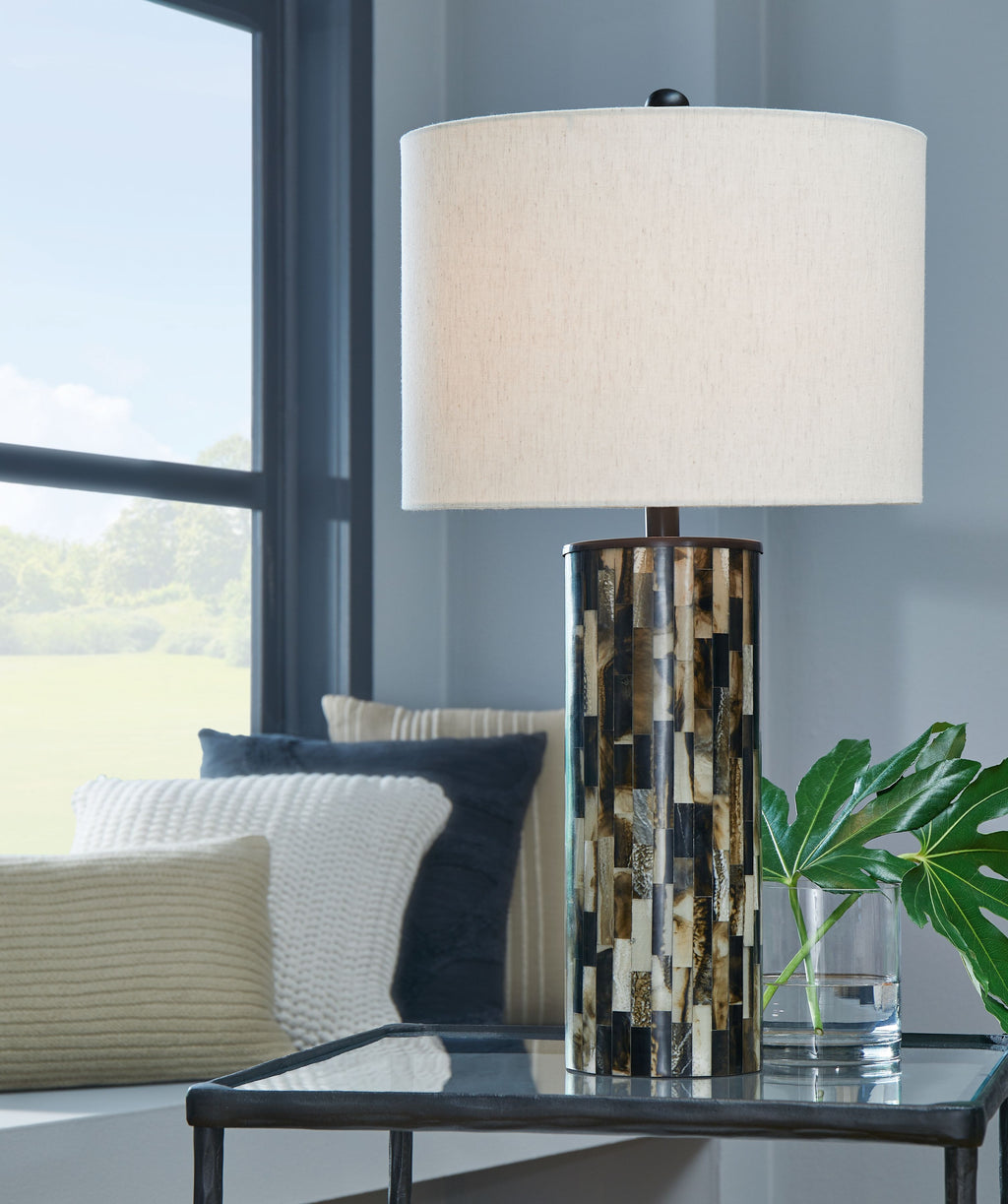 Table lamp with cream shade and cylindrical mosaic base on tabletop
