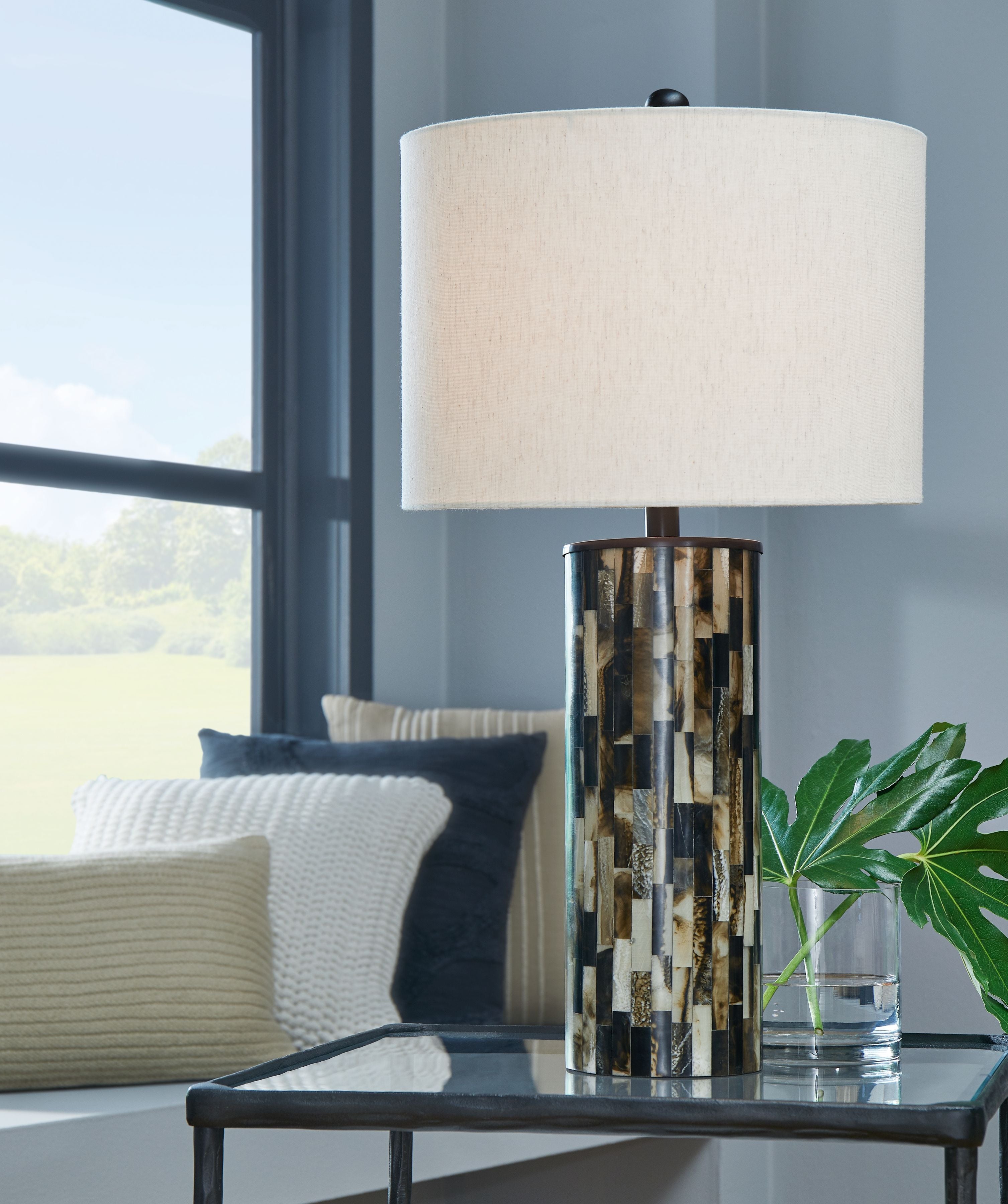 Table lamp with cream shade and cylindrical mosaic base on tabletop