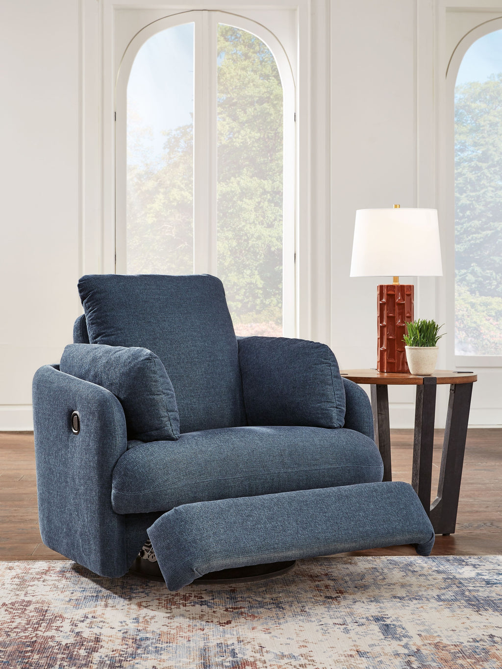 Swivel glider recliner chair in dark blue fabric, side view with padded arm caps.