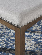 Dining chair corner detail: light upholstered cushion with nailhead trim on dark wood