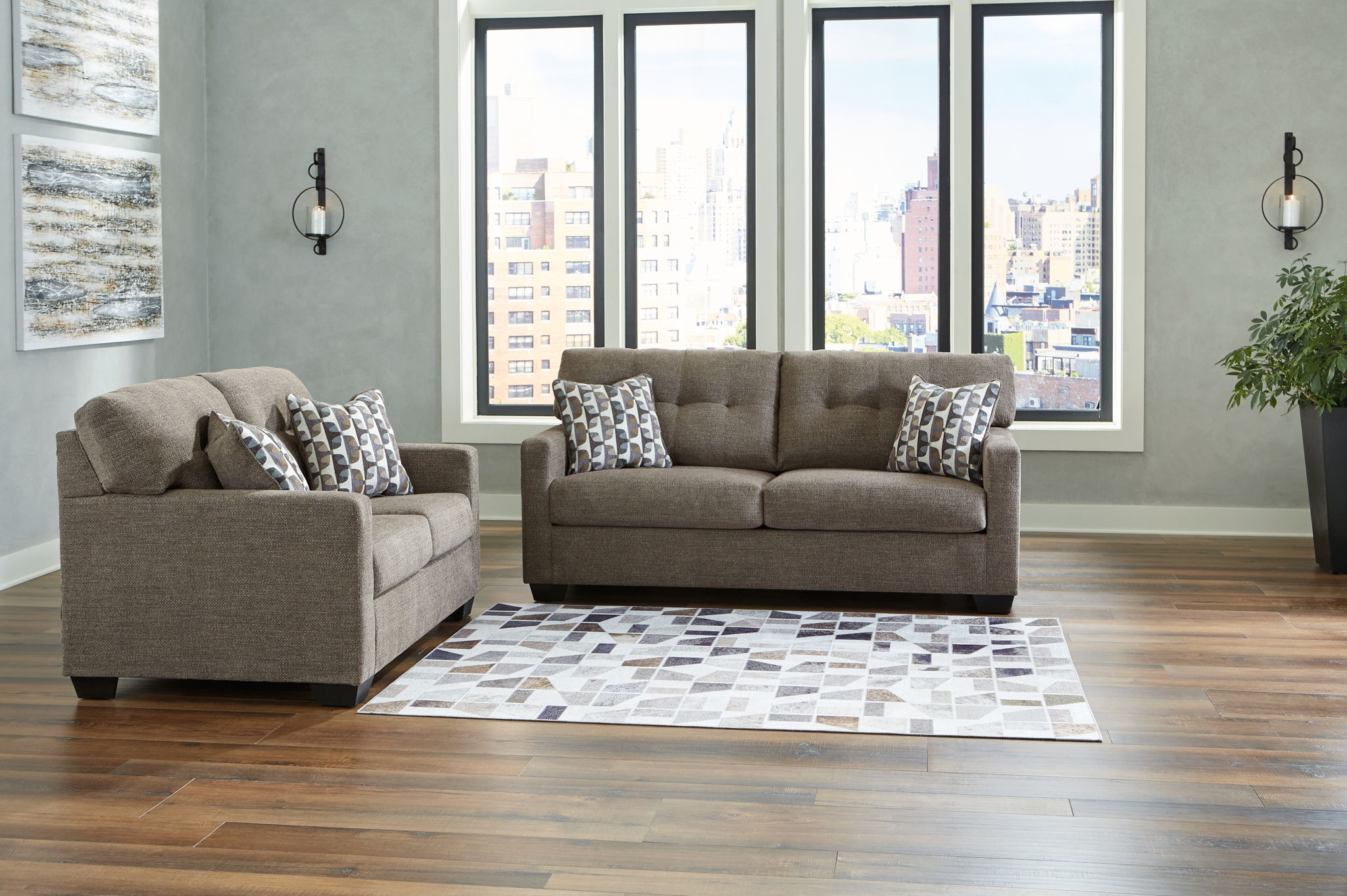 Dark gray sofa set with matching loveseat and patterned throw pillows on dark feet