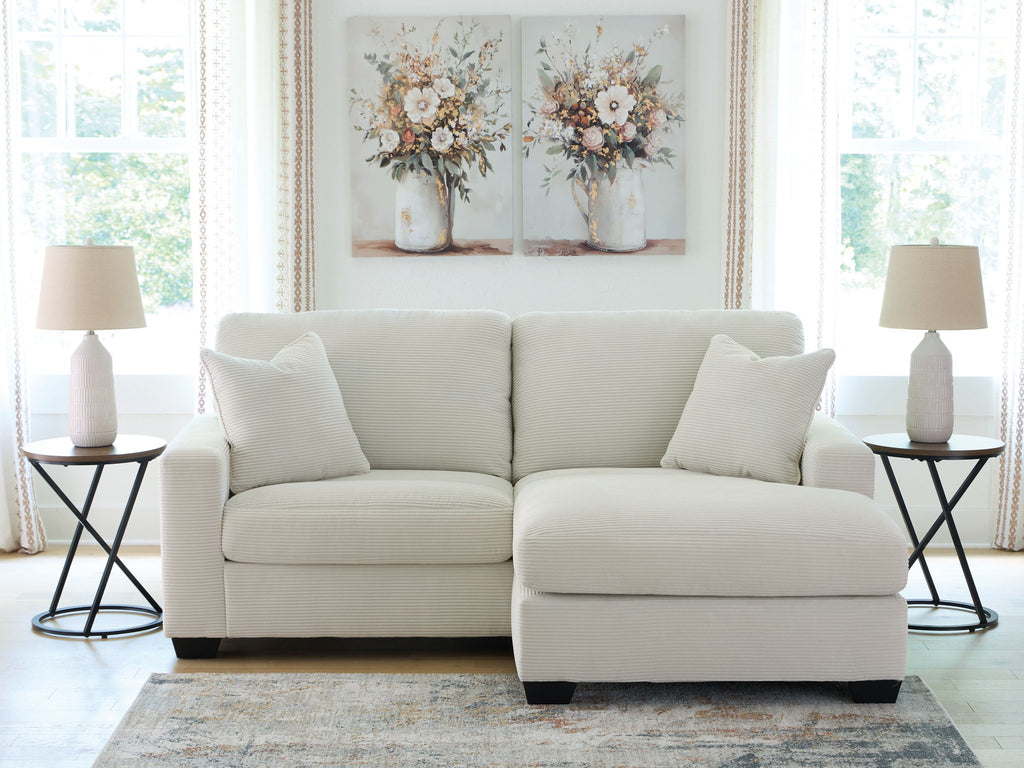 Light gray sofa chaise with four throw pillows and a chaise ottoman extension