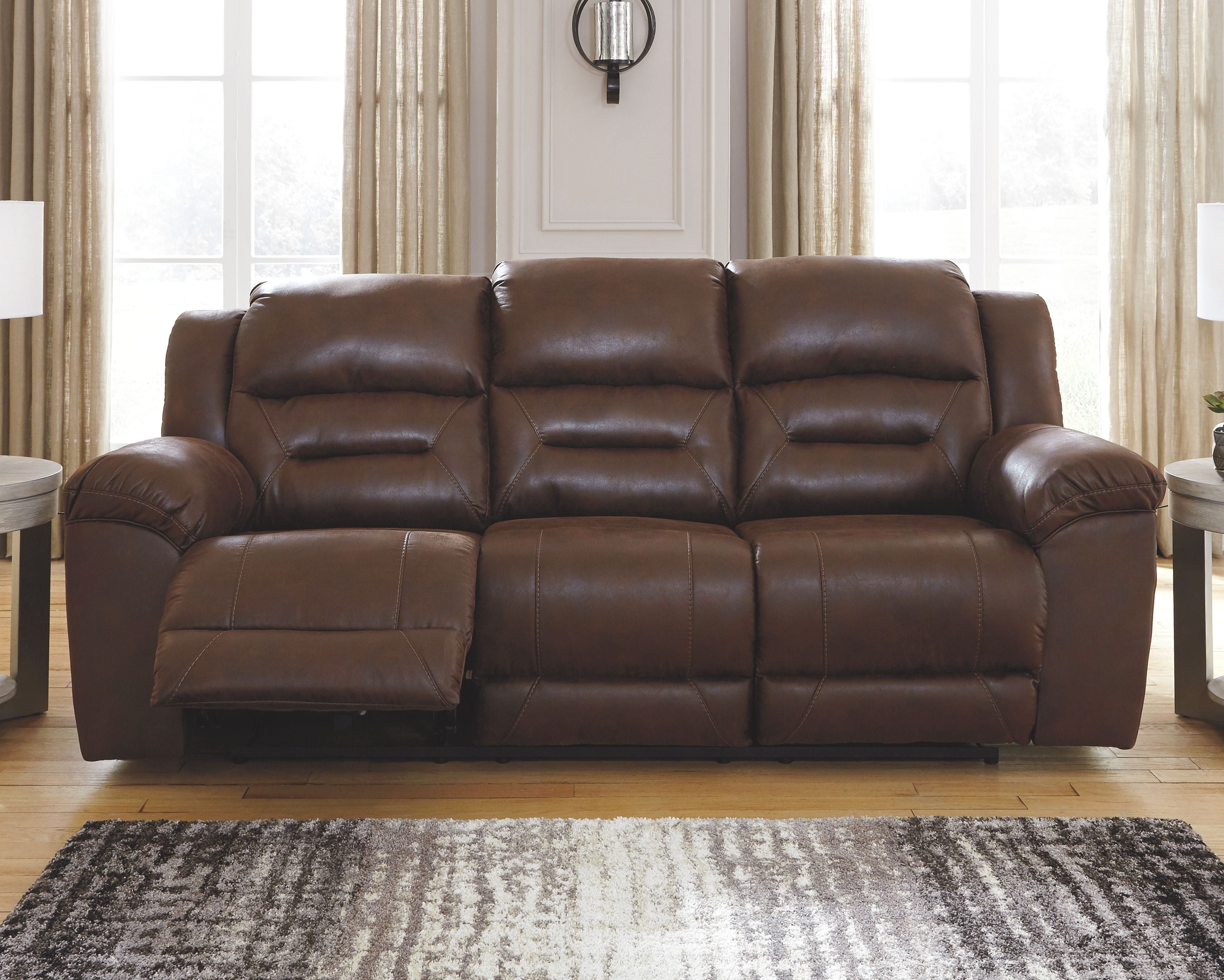 Chocolate brown reclining leather sofa with three seat cushions and deep button tufting