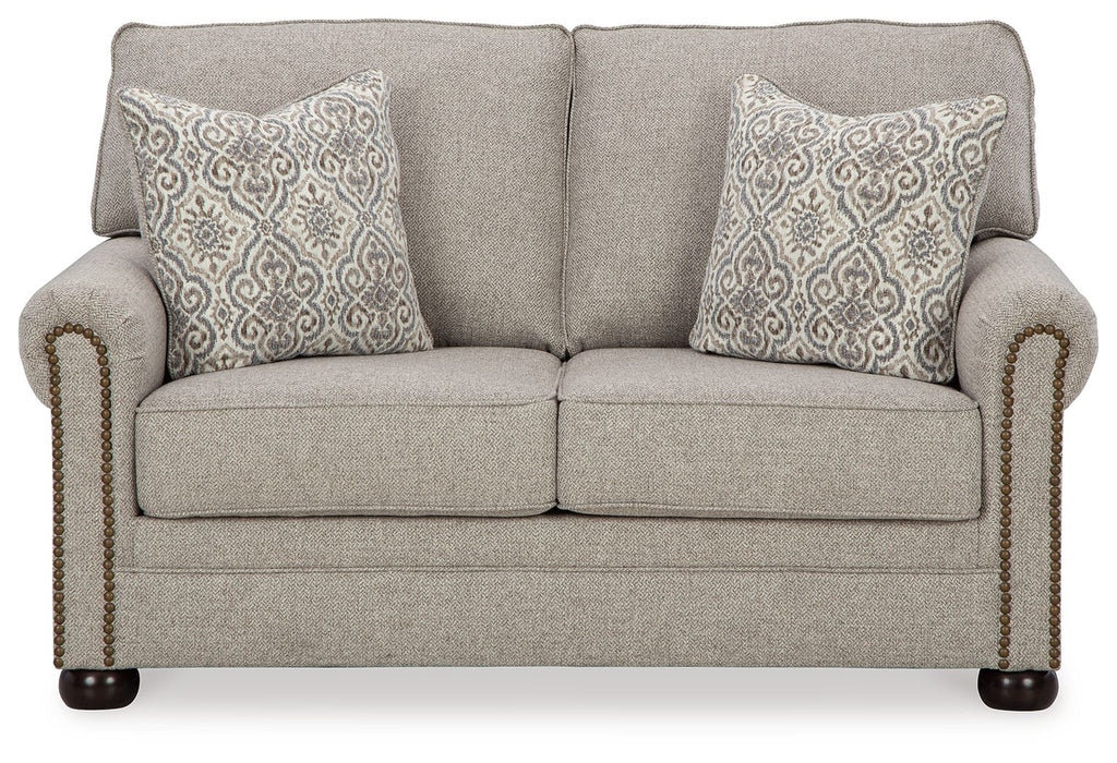 Gray-beige loveseat with two patterned throw pillows, tight back, and rolled arms