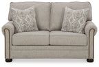 Gray-beige loveseat with two patterned throw pillows, tight back, and rolled arms