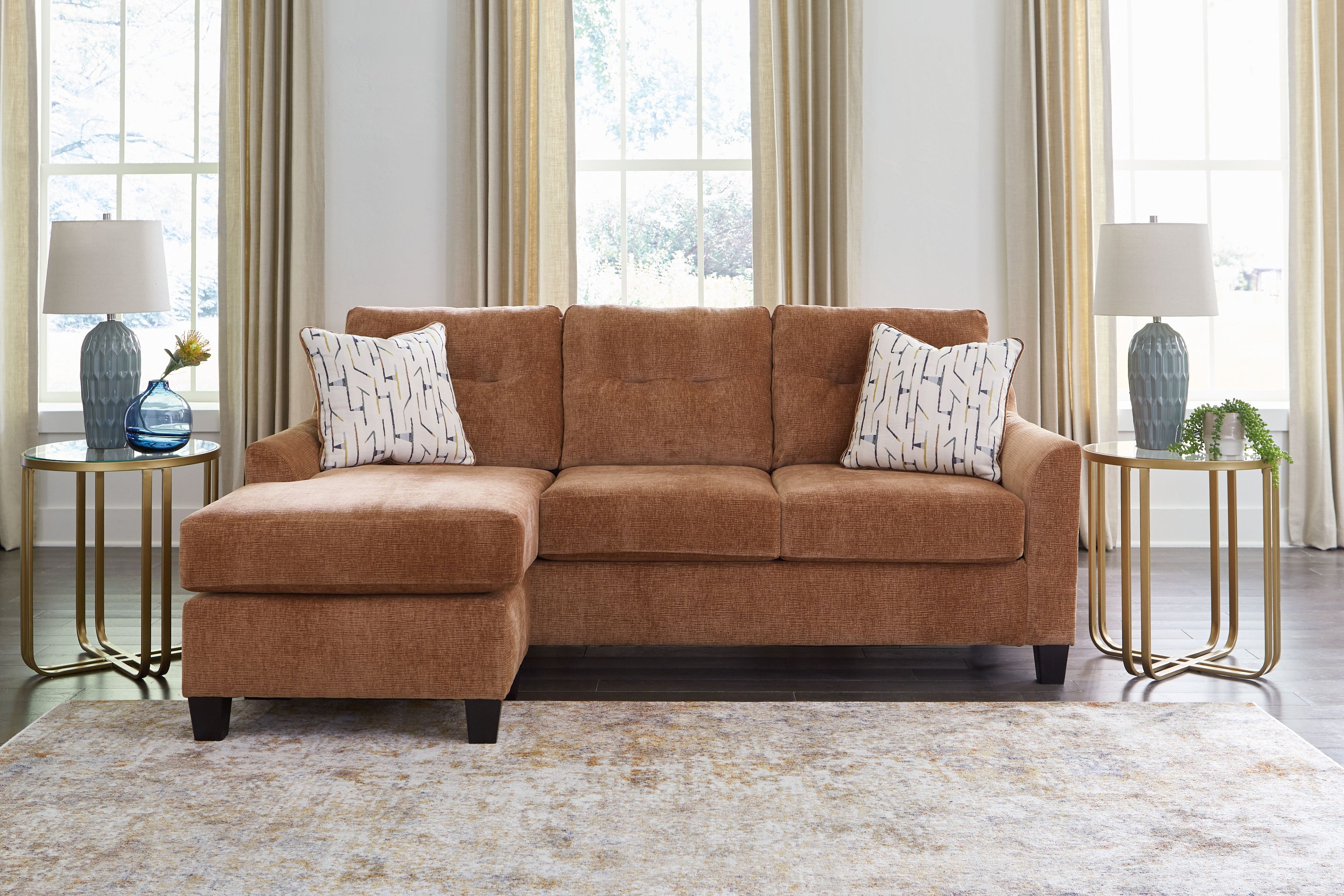 Clay sofa chaise with two patterned pillows, wide chaise seat, and tufted back