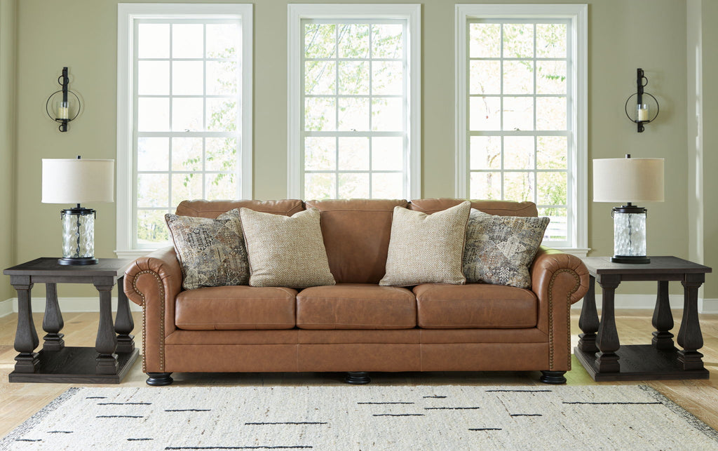 Brown fabric sofa with rolled arms and patterned throw pillows in a living room setup