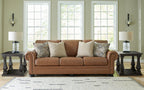 Brown fabric sofa with rolled arms and patterned throw pillows in a living room setup
