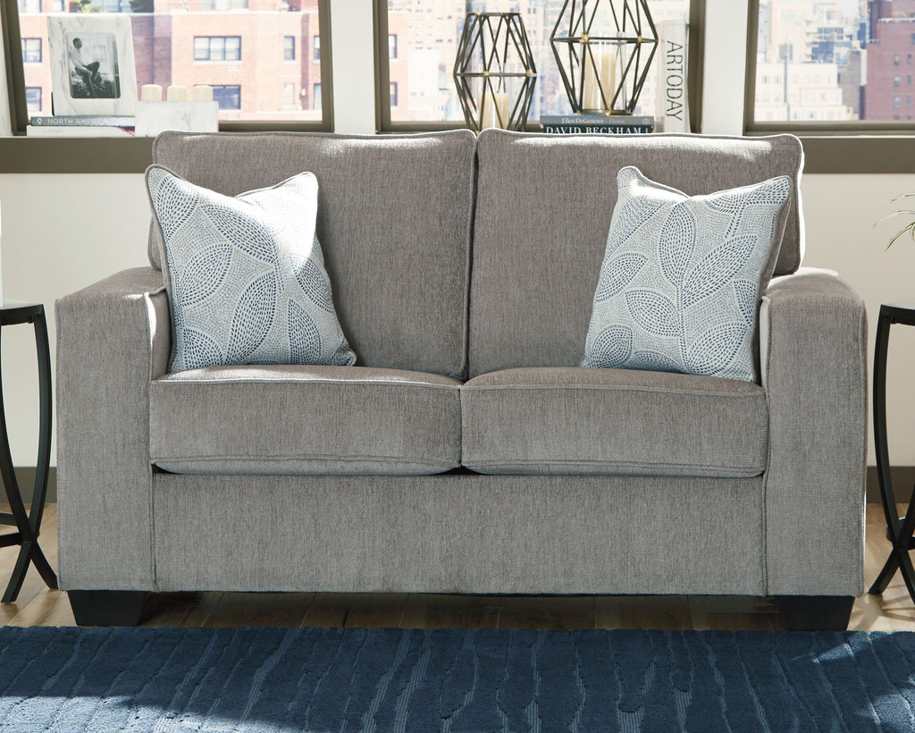 Light gray stationary loveseat with two light blue patterned throw pillows and padded back