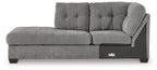 Gray corner chaise sofa with deep tufted cushions, curved arm, and dark legs
