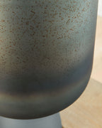 Blue speckled vase close-up of curved body and matte pedestal base.