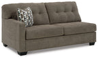 Dark gray-brown upholstered sofa with tufted back, two cushions, black feet.