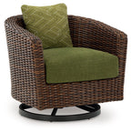 Side view brown woven swivel lounge chair with green seat cushion and patterned back pillow