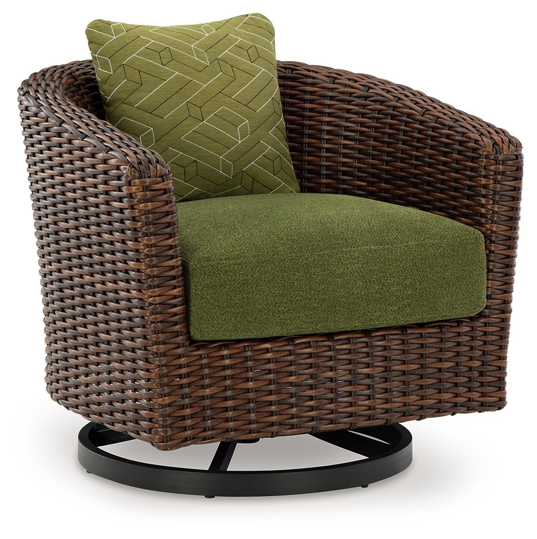 Side view brown woven swivel lounge chair with green seat cushion and patterned back pillow