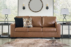 Brown leather sofa with three seat cushions and decorative throw pillows