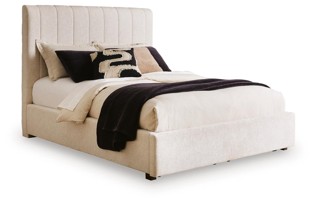 Beige upholstered queen bed with vertical channel headboard and padded frame, white bedding