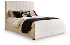 Beige upholstered queen bed with vertical channel headboard and padded frame, white bedding