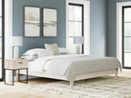 Platform bed with light wood frame and white bedding, raised base and slatted support
