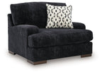 Black chair-and-a-half with rounded arms, thick seat, and patterned accent pillow