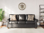 Chasemore sofa in dark gray with two patterned pillows and curved studded arms