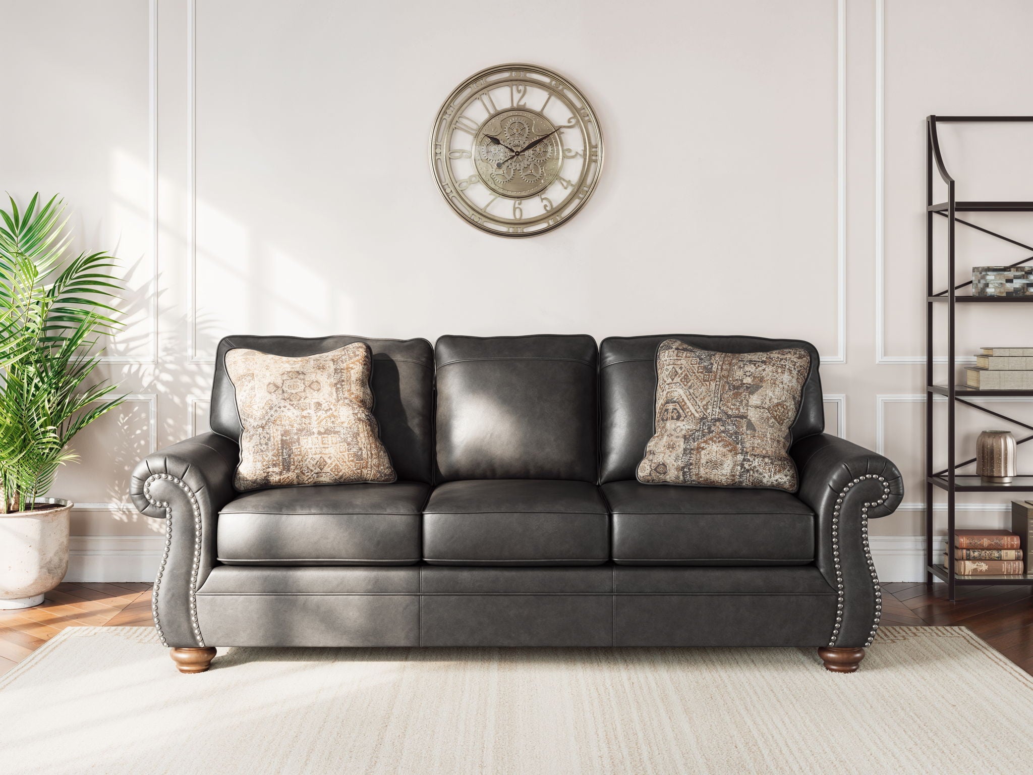 Chasemore sofa in dark gray with two patterned pillows and curved studded arms