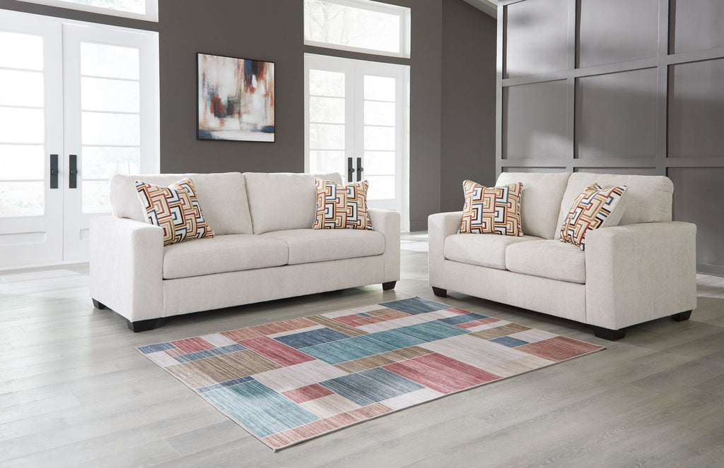 Cream sofa and loveseat with patterned throw pillows