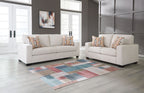 Cream sofa and loveseat with patterned throw pillows