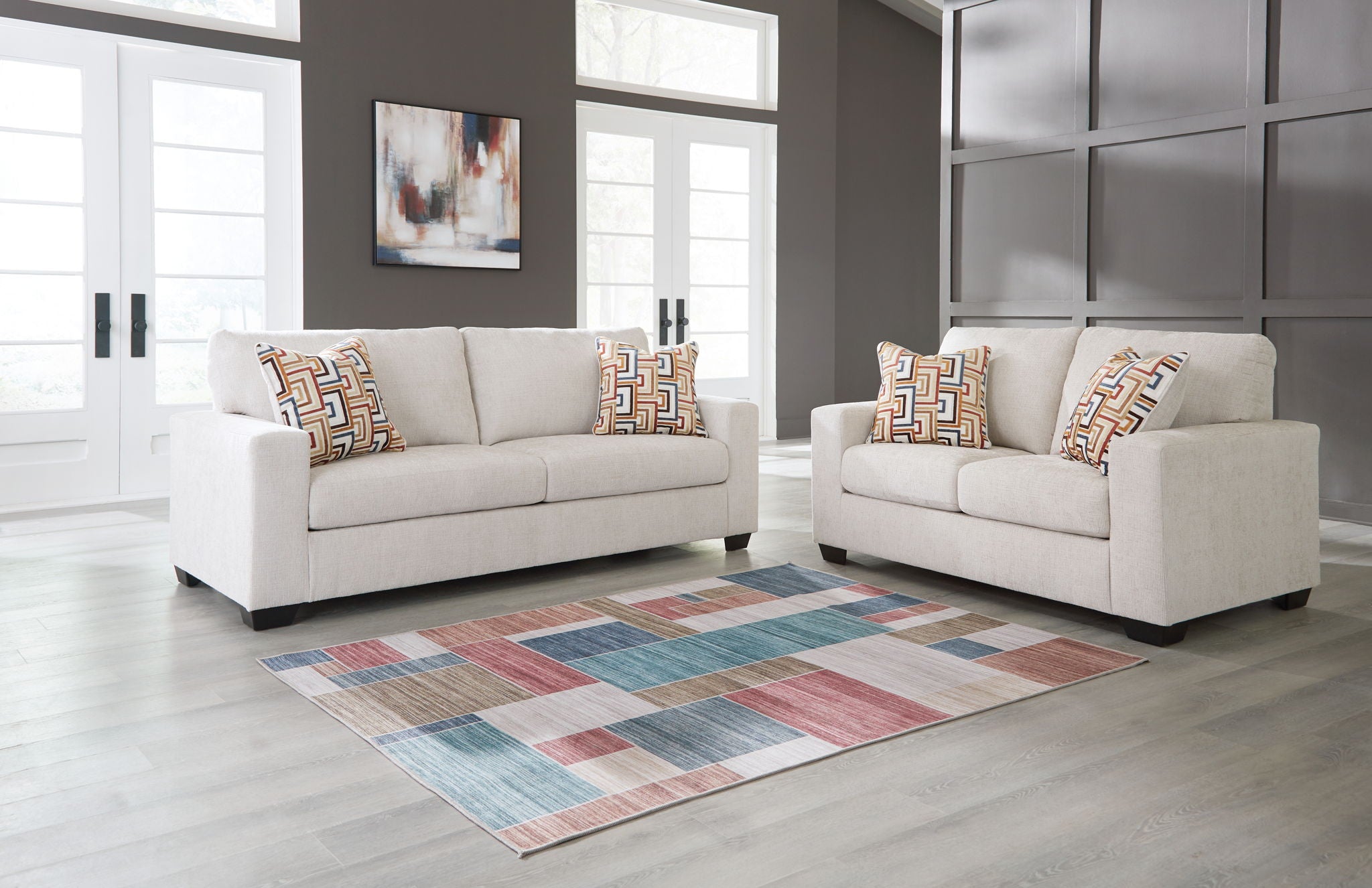 Cream sofa and loveseat with patterned throw pillows