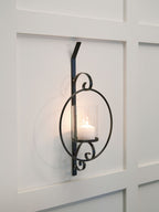 Black wall sconce with clear glass cylinder shade and glowing bulb