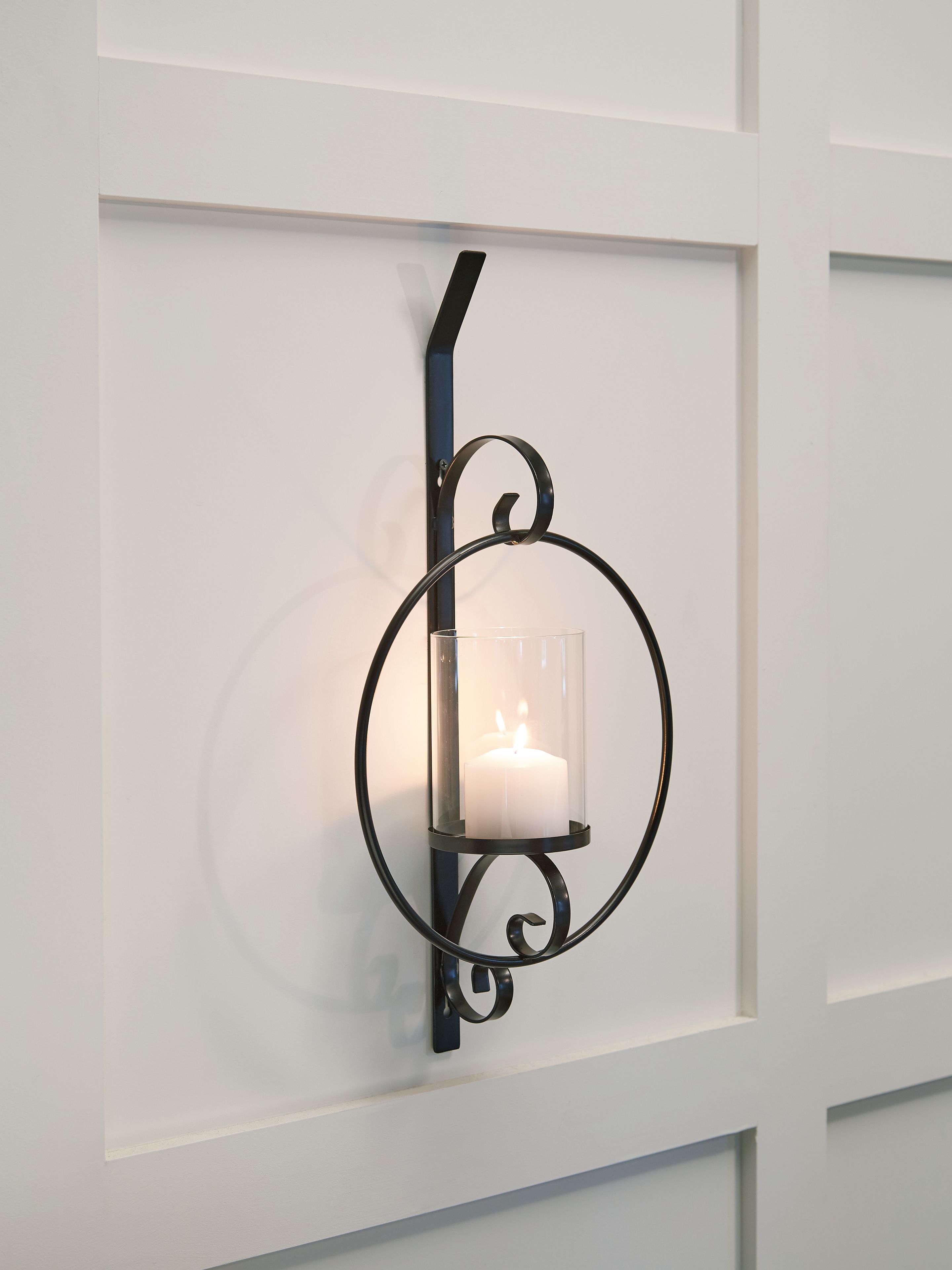 Black wall sconce with clear glass cylinder shade and glowing bulb