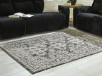 Glennisman rug on floor, large rectangular distressed pattern in light gray and black border