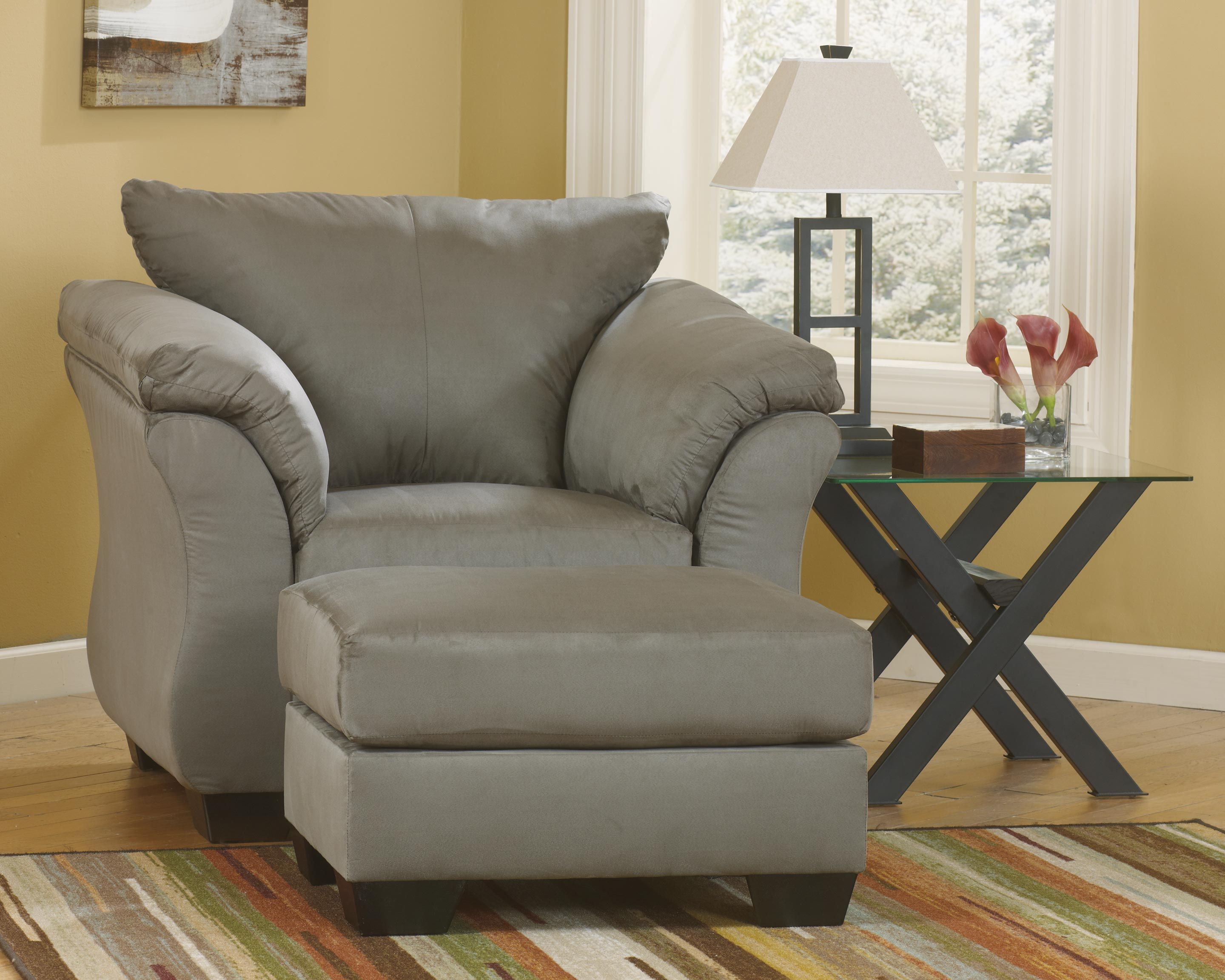 Upholstered ottoman in dark gray fabric, wide cushioned seat and rounded arms.